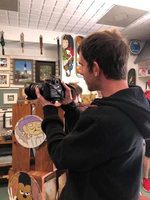 Josh Stewart, a Washed Ashore member, helps out by photographing the items for sale.
