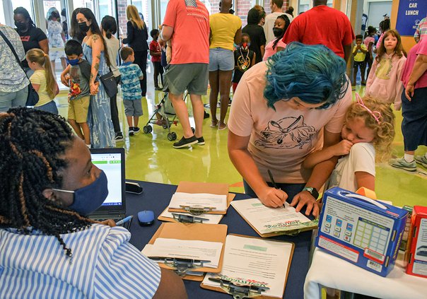 Kindergartener Harper Willis, 5, snuggles with mom Cheyenne as they check in with family engagement specialist Sharon Wilkins, left, during open house at Mattie Lively Elementary School on Thursday, July 29. All Bulloch County schools open the doors to we