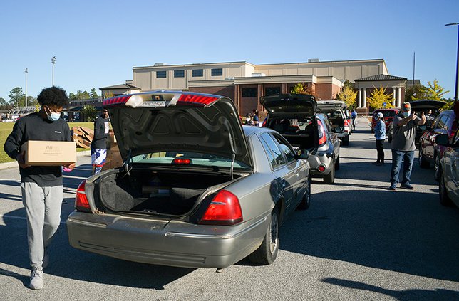 During the 2020 Thanksgiving food drop, Feed the Boro volunteer Joshua Johnson, left, loads up a box of groceries as cars wind around Statseboro High School. Feed the Boro's 2021 Thanksgiving food drop is set for Saturday at 9 a.m. again at SHS.