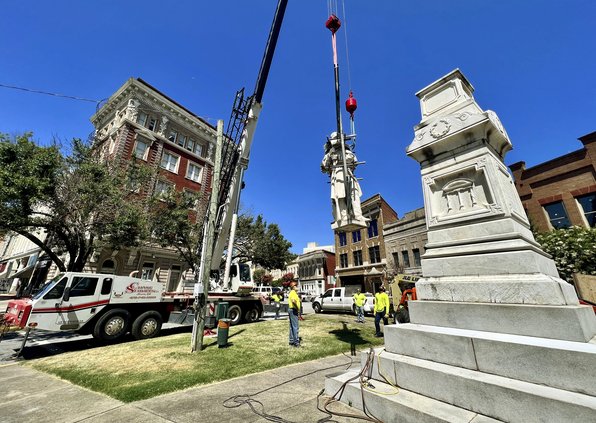 Crews lower the Confederate monument on Cotton Ave. in Macon, Ga., while removing it Wednesday, June 22, 2022. The monument will be relocated to Whittle Park in front of Rose Hill Cemetery.