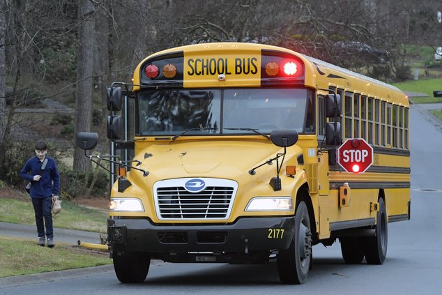 A Cobb County School bus moves on street Friday, March 13, 2020, in Kennesaw, Ga. Georgia's second-largest school district on Thursday, July 14, 2022 approved a policy allowing some employees who aren't certified police officers carry guns in schools, but