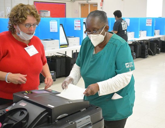 Poll worker Tina Douzenis, left, helps Johnnie Mae Atkinson cast her paper ballot while fellow voters make their selections at the William James Complex in this file photo from November 2021. Like most of Georgia and the nation, Bulloch County is in criti