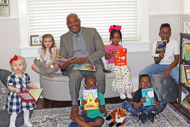 Statesboro Mayor Jonathan McCollar enjoys spending some time looking at and reading books with local children in the city of Statesboro's Reading Nook.