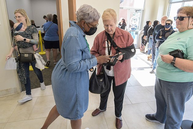 Poll worker Edith Penny, center left, helps Beverly Emmitt remove a stubborn drivers license from her wallet during early voting in the Georgia U.S. Senate runoff at the Bulloch County Annex on Tuesday, Nov. 29.