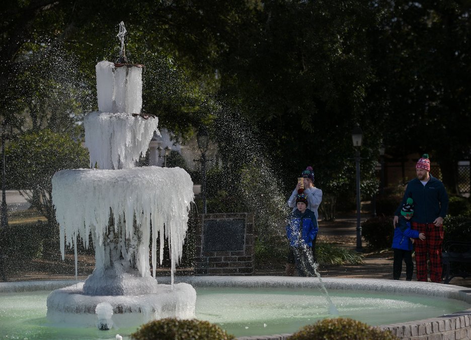 Heavy winter storm blanketing a backyard fountain and surrounding landscape in fresh snow