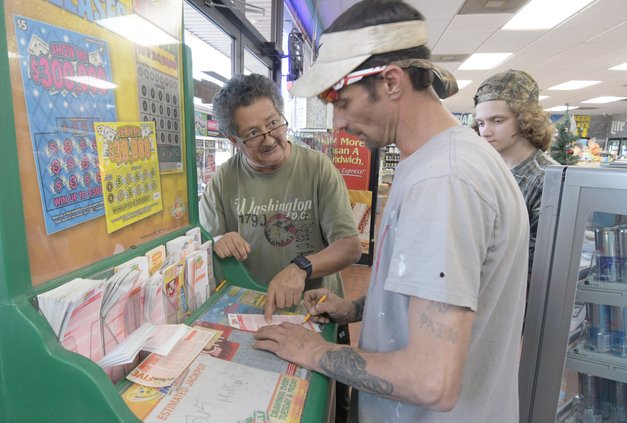 Fast & Easy owner/operator Kamal Dreid, left, helps customer James Best and son Jace, 17, fill out a lottery ticket on Monday, Jan. 2 as the Mega Millions jackpot is expected to surpass $800 million.