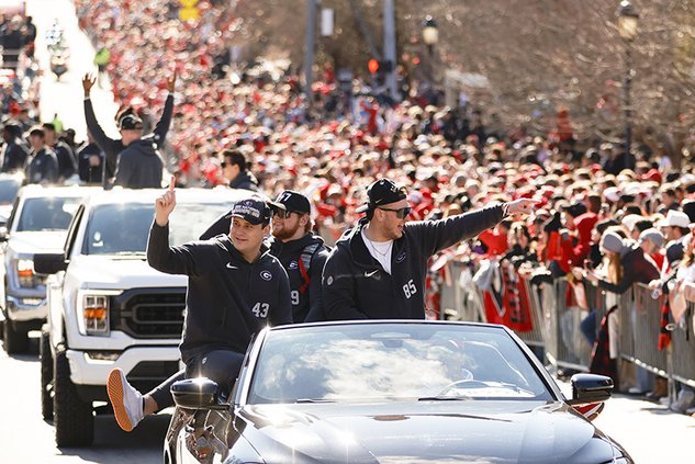 Georgia football players acknowledge the crowd during a parade celebrating the Bulldog's second consecutive NCAA college football national championship Saturday in Athens. A player from the team and a recruiting assistant were killed in a traffic accident