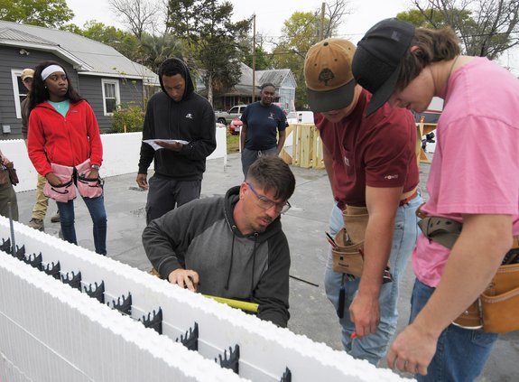 Homeowner to-be Maria Lipsey, backround center, watches as Habitat for Humanity of Bulloch County construction manager Aaron Marcinkevich, bottom center, teaches building techniques using insulating concrete forms to Georgia Southern University and Ogeech