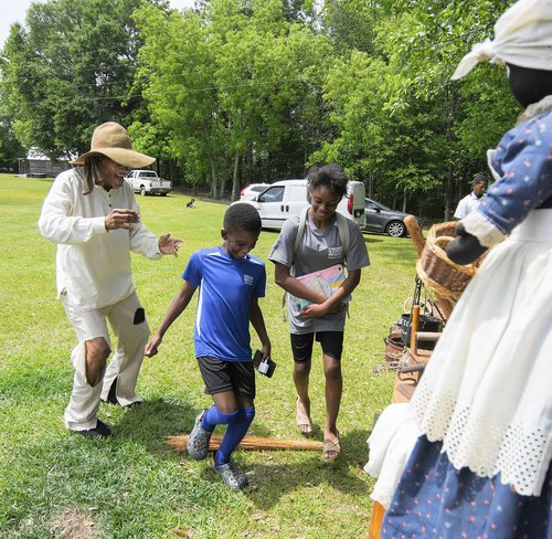 LEFT, storyteller and re-enactor Bruce Ingram of Savannah invites Mayson English, 9, and Denise Browlowe, 11, to perform the broom ceremony while teaching about the lives of slaves in America. Ingram jokingly assured everyone that the two youngsters were