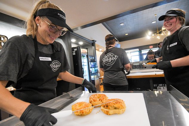 Maria Phillips, left, keeps the supply of sliced bagels coming as Natalie Grant, right, and Shawnee Waters ready the toppings at a Boro Bagel Company private event on Tuesday, Sept. 5.
