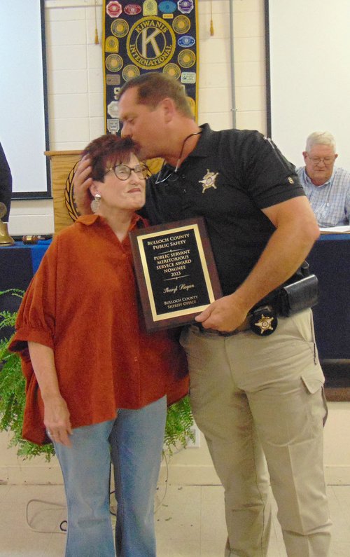 Sheryl Hagan, left, soon to retire after 50 years as administrative assistant to Bulloch County's elected sheriffs, gets the Meritorious Service Award and an appreciative kiss from current Sheriff Noel Brown