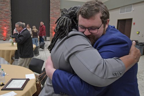 After being named Ogeechee Technical College 2023 Georgia Occupational Award of Leadership (GOAL) winner, cyber security student Justin Clenny gets a big hug, some words of advice and congratulations from 2022 winner Ann Hester while father David, backgro