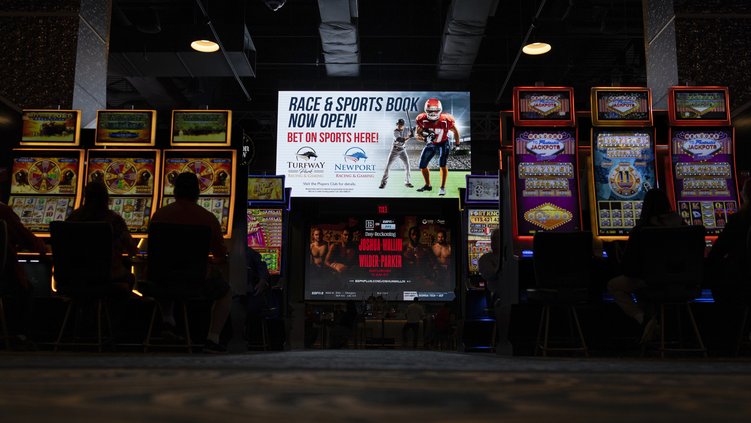 A huge TV screen at the entrance of Churchill's Bourbon & Brew Bar & Grille, flanked by electronic gaming machines, promotes sports betting at Turfway Park Racing & Gaming, Friday, Dec. 22, 2023, in Florence, Ky. Lawmakers in a Georgia Senate committee re