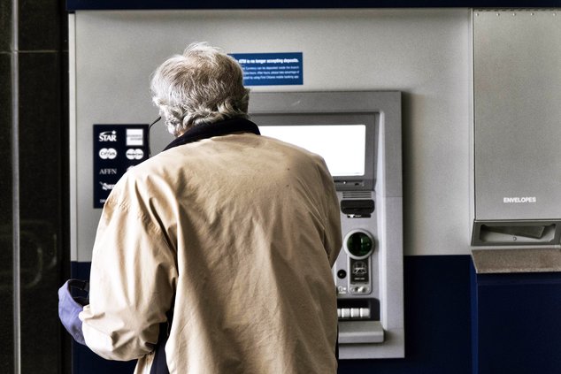 A customer makes a transaction at an automatic teller machine in Los Angeles in March 2023. The cost to overdraw a bank account could drop to as little as $3 under a proposal announced by the White House, the latest move by the Biden administration to com