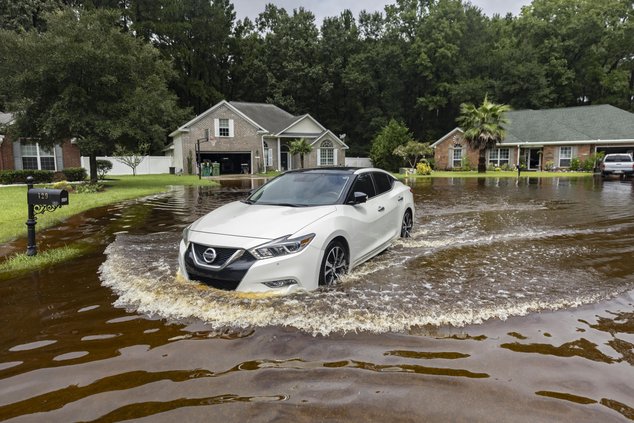 Keon Johnson leaves his house on his way to work down a street that flooded on Monday from Tropical Storm Debby and still hasn't drained, Wednesday, Aug. 7, 2024, in Pooler, Ga.