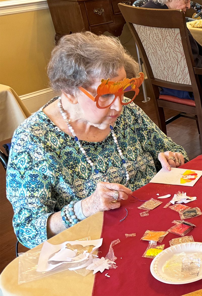 resident Anne Starling works on an arts and craft activity to make turkeys using different colored sand during the Fall Festival.