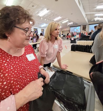 The Button founder Liz Corbett, right, answers questions from volunteers at Tuesday’s packing.