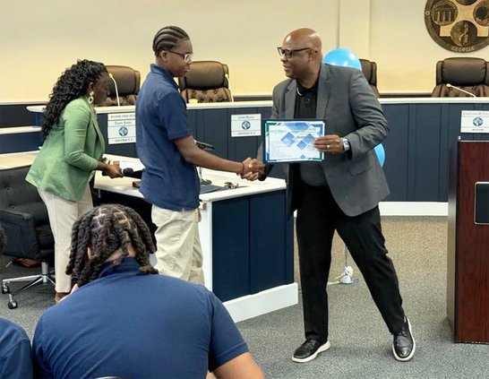 Statesboro Mayor Jonathan McCollar congratulates Mekhi Phillips, a 10th-grader at Statesboro High School and awards him a certificate for completing the annual Statesboro Youth Connect summer program during June 25 graduation ceremonies for the class at C