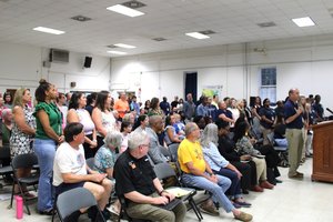 Teachers attending Wednesday's special meeting of the Bulloch County Board of Education stand at the request of Transitions Learning Center Administrator Tim Rountree, at lectern, as he speaks for keeping the TLC open and not cutting teaching jobs.
