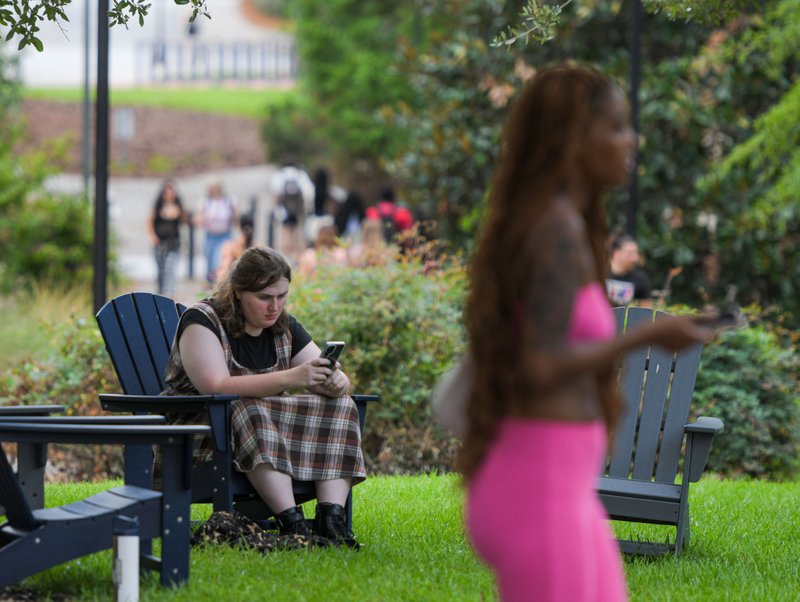 Georgia Southern sophomore Daisy Hughes takes advantage of some Adirondack-style chairs placed along campus walkways while waiting for extracurricular clubs to begin while classmates shuttle between classes on the first day of the 2025 Fall semester on We